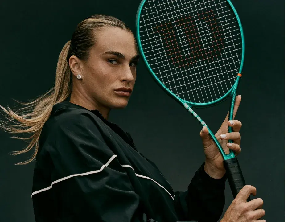 A professional player holding a green Wilson Blade tennis racket